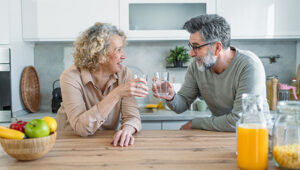 Cheerful mature couple drinking water and relaxing in the kitchen at home